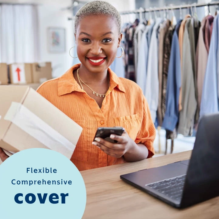 A female business owner wearing a red apron working on a laptop at a retail or small business setting. Her business is covered with flexible comprehensive cover from Momentum Insure's business insurance.